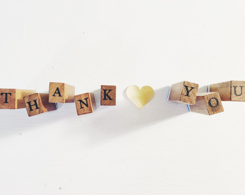 Holzbuchstaben bilden den Satz "THANK YOU", wobei ein kleines Herz zwischen "K" und "Y" platziert ist.